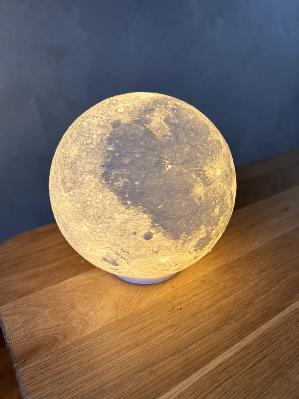 Upaljena lampa Mjesec s reljefnom površinom na drvenoj podlozi.