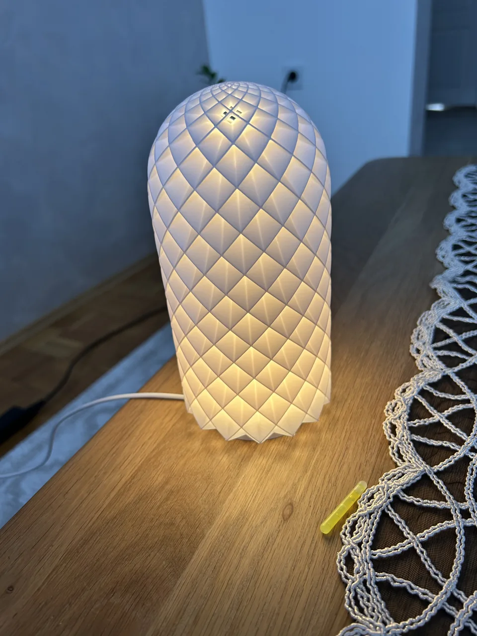 Upaljena cilindrična lampa s reljefnim geometrijskim uzorkom.